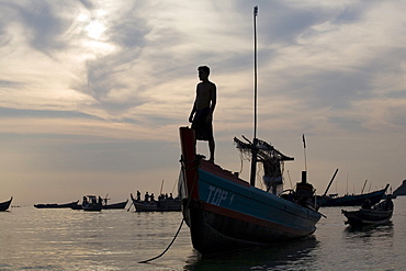 Man standing on a fishing boat in the sunset in Ngapali Beach, Gulf of Bengal, Rakhine State, Myanmar, Burma