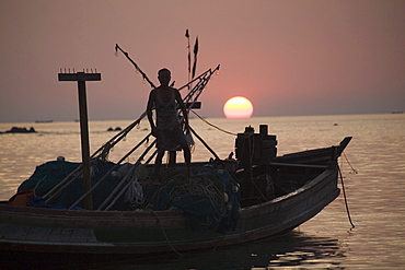 Man standing on a fishing boat at sunset in Ngapali Beach, Gulf of Bengal, Rakhine State, Myanmar, Burma