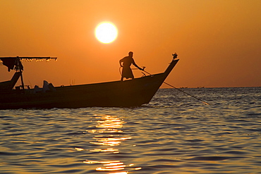 Man standing on a fishing boat at sunset in Ngapali Beach, Gulf of Bengal, Rakhine State, Myanmar, Burma