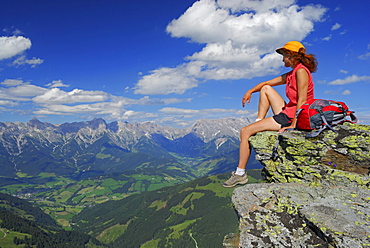 young woman sitting on rock with Steinernes Meer range and Hochkoenig in Berchtesgaden range in background, Hundstein, Salzburger Schieferalpen range, Salzburg, Austria