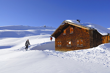 skiers arriving at snow-covered alpine hut, Schwarzwassertal, Kleinwalsertal, Allgaeu range, Allgaeu, Vorarlberg, Austria