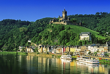 Reichsburg under blue sky and excursion boats at the riverbank, Mosel, Rhineland-Palatinate, Germany