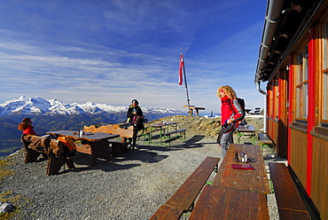 Three women on terrace in front of hut Statzer Haus on Hundstein, view to Hohe Tauern range, hut Statzerhaus, Dientner Schieferberge range, Dientner Schieferalpen range, Salzburg, Austria