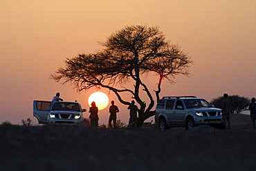 People and all-terrain vehicles in front of the setting sun, Al Hajar mountains, Oman, Asia