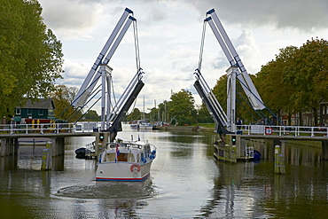 A motorboat on the river Vecht driving past a bascule bridge, Netherlands, Europe