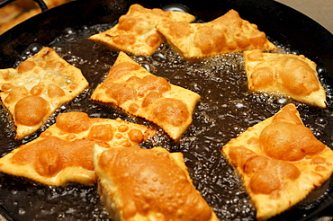 Doughnuts in hot oil in a frying pan, South Tyrol, Italy, Europe