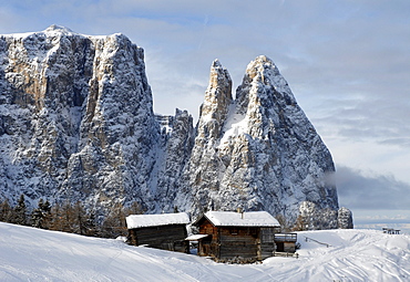 Alpine huts in front of snow covered mountains, Alpe di Siusi, South Tyrol, Italy, Europe