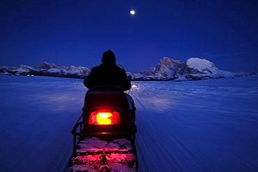 Man on a skidoo at night, Langkofel Mountain Range, South Tyrol, Italy