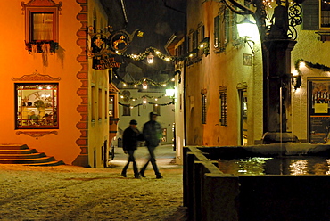 Kastelruth in Winter, village square piazza Kraus, Krausplatz with fountain and Christmas tree at night, Kastelruth, Castelrotto, South Tyrol, Italy