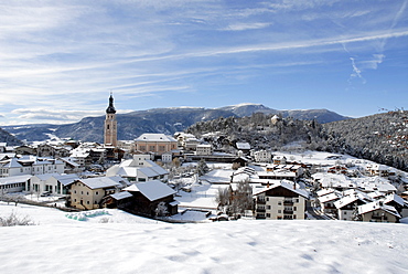 Snow covered houses and church of the village Kastelruth in the sunlight, South Tyrol, Italy, Europe