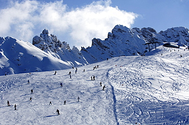 View at skiers on a ski slope under clouded sky, Alpe di Siusi, Dolomites, South Tyrol, Italy, Europe