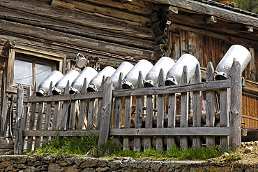 Milk churns on a wooden fence in front of alpine hut, Schnals valley, Val Venosta, South Tyrol, Italy, Europe