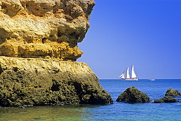 Sailing ship off the rocky coast under blue sky, Praia do Camilo, Algarve, Portugal, Europe