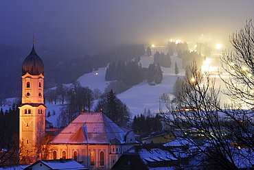 View over St. Andreas church to illuminated slope, Nesselwang, Bavaria, Germany