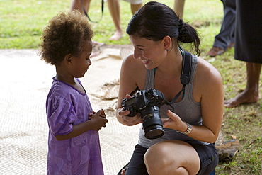 Young woman showing pictures on her camera to fijian child, Naidi, Vanua Levu, Fiji Islands, South Pacific, Oceania