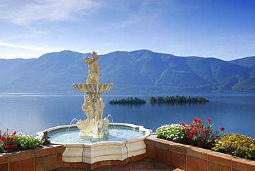 Lake Maggiore with isle of Brissago, Isole di Brissago, and Monte Gambarogno with fountain and flowers in the foreground, Ronco sopra Ascona, lake Maggiore, Lago Maggiore, Ticino, Switzerland