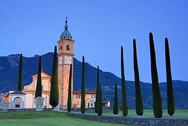 Illuminated church San Abbondino near Gentilino with cypress alley, Gentilino, Lugano, Ticino, Switzerland