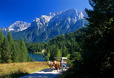 Horse-drawn carriage in the sunlight in front of lake Lautersee and Karwendel mountains, Bavaria, Germany, Europe