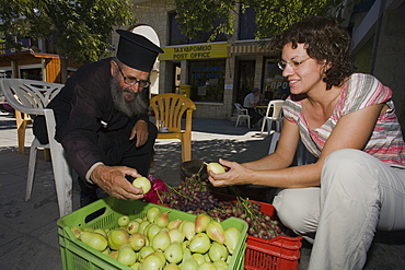 Monk, Priest selling fruit, Woman buying fruit at the market stall, Geroskipou, near Pafos, South Cyprus, Cyprus