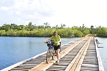 Woman is pushing her mountainbike in the masoala national park in madagaskar, africa