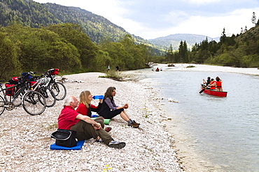 Cyclists resting at river Isar, Isar Cycle Route between Wallgau and Vorderriss, Karwendel range, Upper Bavaria, Germany