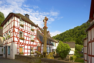 Crucifix with lions on the bridge over the river Elz, Half-timbered house, Monreal, Eifel, Rhineland-Palatinate, Germany, Europe