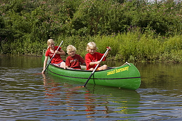 Three children paddling a canoe on the river Fulda, Niederaula, Hesse, Germany, Europe