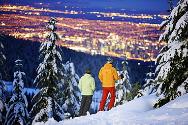 Skiers looking over Vancouver in the evening, British Columbia, Canada