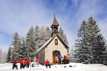 People in front of chapel on winter hiking trail in snowy landscape, Hemmersuppenalm, Reit im Winkl, Chiemgau, Bavaria, Germany, Europe