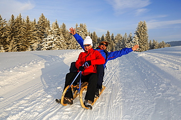 Couple sledging on winter hiking trail in snowy landscape, Hemmersuppenalm, Reit im Winkl, Chiemgau, Bavaria, Germany, Europe