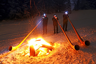 Alphorn players at a bonfire in the snow, Hemmersuppenalm, Reit im Winkl, Chiemgau, Upper Bavaria, Bavaria, Germany, Europe