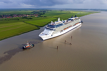 Tug boat navigating the newly launched Celebrity Equinox from the Meyer Werft along the River Ems, Lower Saxony, Germany