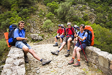 hikers on the old genovese stone bridge over the River Porto near the village of Ota, Spelunca Gorges, Corsica, France, Europe, not free for advertising