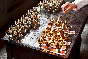 Oil lamps and butter lamps, woman lighting a candle, buddhist ritual, Luohan Temple, buddhist temple downtown, Chongqing, People's Republic of China