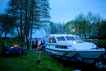 People having a barbeque on the banks of lake Ellbogensee, Houseboat, near Fuerstenberg/Havel, Mecklenburg Lake District, Mecklenburg-Pomerania, Germany