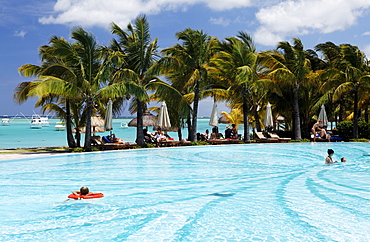 People and palm trees at the pool of Beachcomber Hotel Paradis & Golf Club, Mauritius, Africa