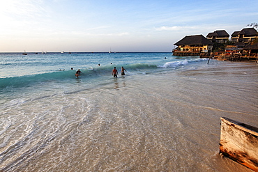 Bathing people and the Z Hotel at dusk, Nungwi, Zanzibar, Tanzania, Africa