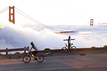 Cyclist embracing the sun, Golden Gate Bridge in fog, Symbol of San Francisco and California, San Francisco, California, United States of America, USA