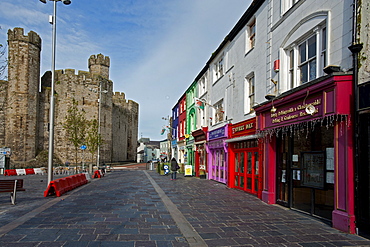 Caernarfon Castle with shops and restaurants, Caernarfon, Wales, UK