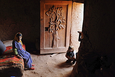 Old Berber woman and young European girl in traditional Berber house with adorned door, Kasbah Ait Benhaddou, Ait Benhaddou, Atlas Mountains, South of the High Atlas, Morocco, Africa