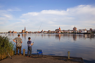 Angler at riverbank, view over Warnow river to the Old Town and St MaryÂ¥s church, Rostock, Baltic Sea, Mecklenburg Western-Pomerania, Germany, Europe