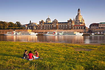 Young women having picnic at the Elbe river, Bruehlsche Terrasse and Frauenkirche in the background, Dresden, Saxonia, Germany, Europe