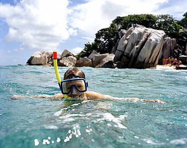 Snorkelling in shallow water over coral reef off tiny Coco Island, La Digue and Inner Islands, Republic of Seychelles, Indian Ocean