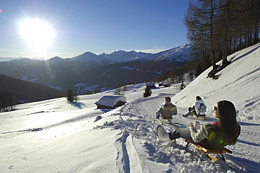 People sledding downhill in snowy mountain scenery, Alto Adige, South Tyrol, Italy, Europe