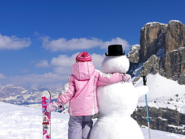 Little girl with skis an snowman, Alto Adige, South Tyrol, Italy, Europe