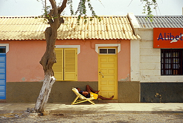 Teenager asleep in a deck chair, Street in Santa Maria, Santa Maria, Sal, Cape Verde Islands, Africa