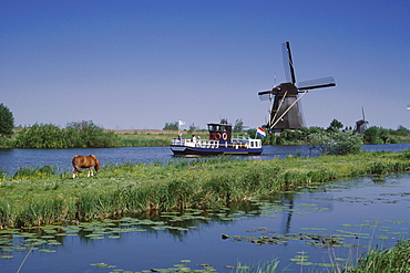 Windmill at a riverbank, Kinderdijk, Netherlands, Europe