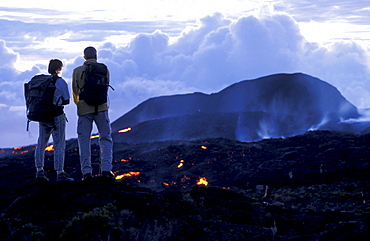 Two people watching glowing lava at Piton Kapor volcano, Ille de la RÃˆunion, Indian Ocean