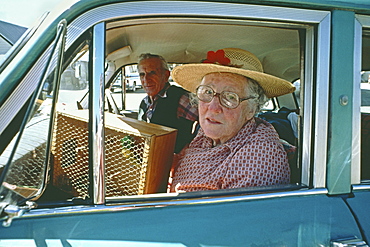 Old couple with budgie in vintage car, South Island, New Zealand