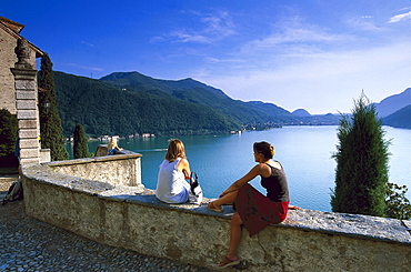 Two people enjoying view from church Santa Maria del Sasso, Morcote, Lago di Lugano, Ticino, Switzerland